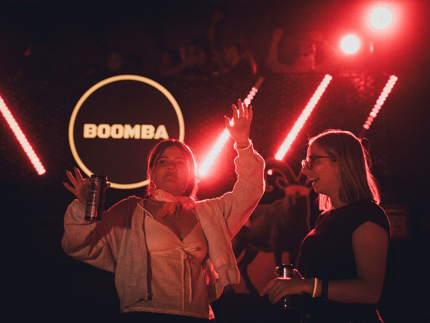 Dancers under red light with the glowing BOOMBA sign